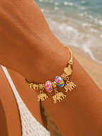 Bracelet jonc talisman doré charmes éléphants perles multicolores roses, porté au soleil bord de mer