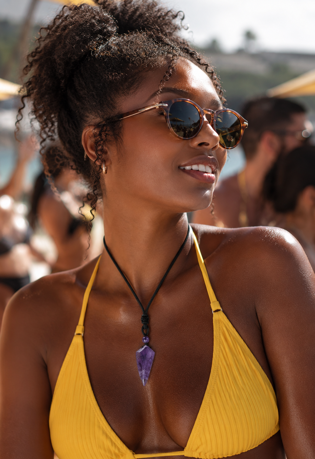 Collier pendentif améthyste violette porté sur bikini jaune — plage foule lumière dorée été — MITCH par AEF