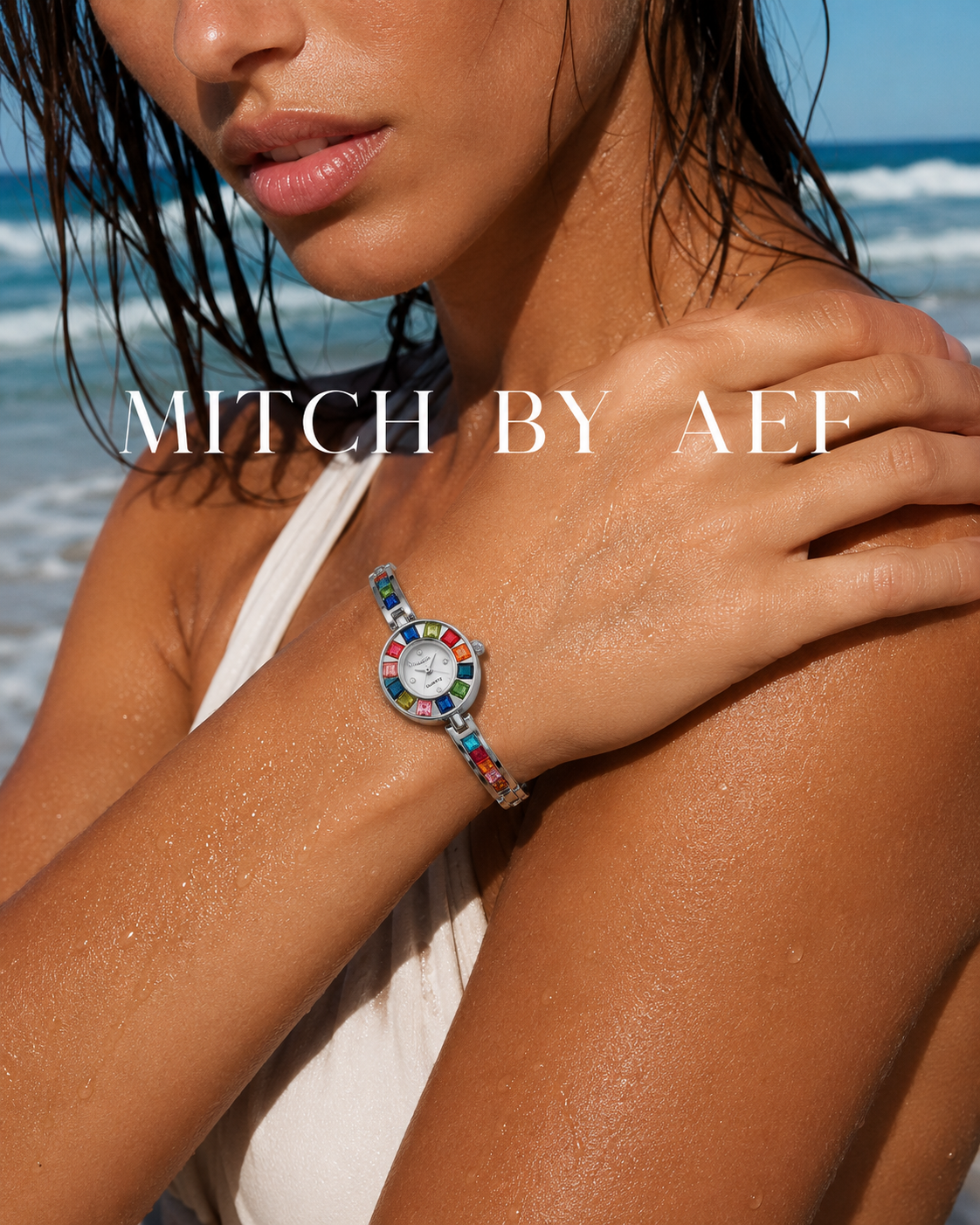 Montre bijou ÉCLAT argentée Cristal Lunaire au poignet d'une femme face à l'océan, cadran à strass multicolores et bracelet fin en alliage argenté, collection MITCH By AEF
