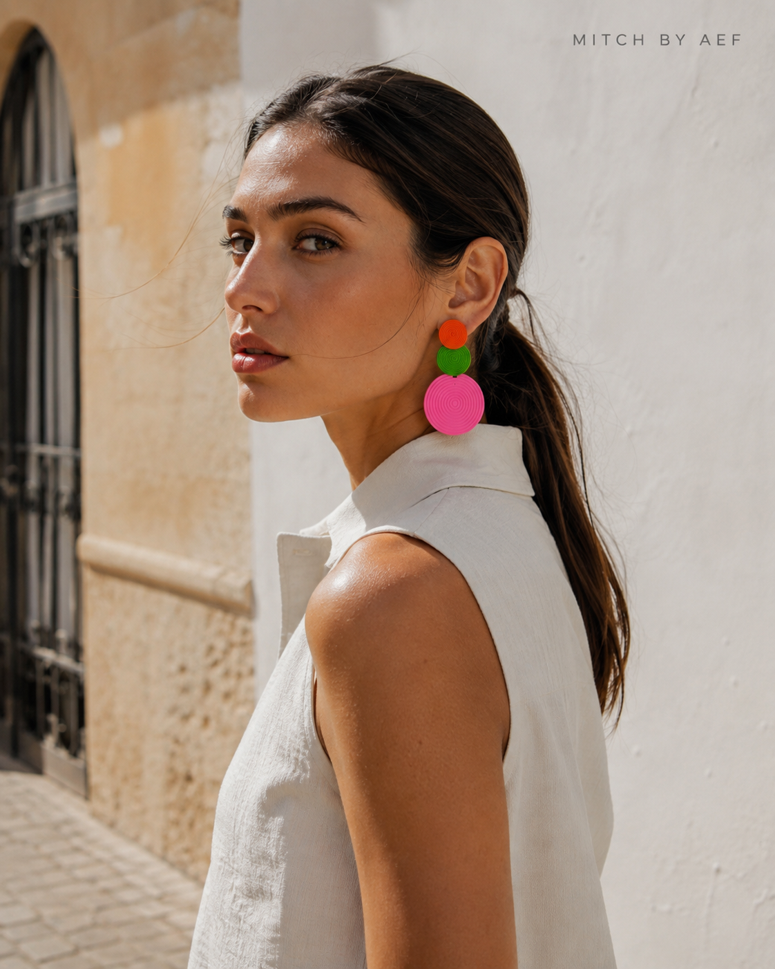 Boucles d’oreilles ORBIS orange, vert et rose à trois disques portées par une femme