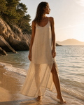 Robe maxi fluide crème bretelles fines, femme bronzée cheveux bouclés de face plage golden hour mer bleue