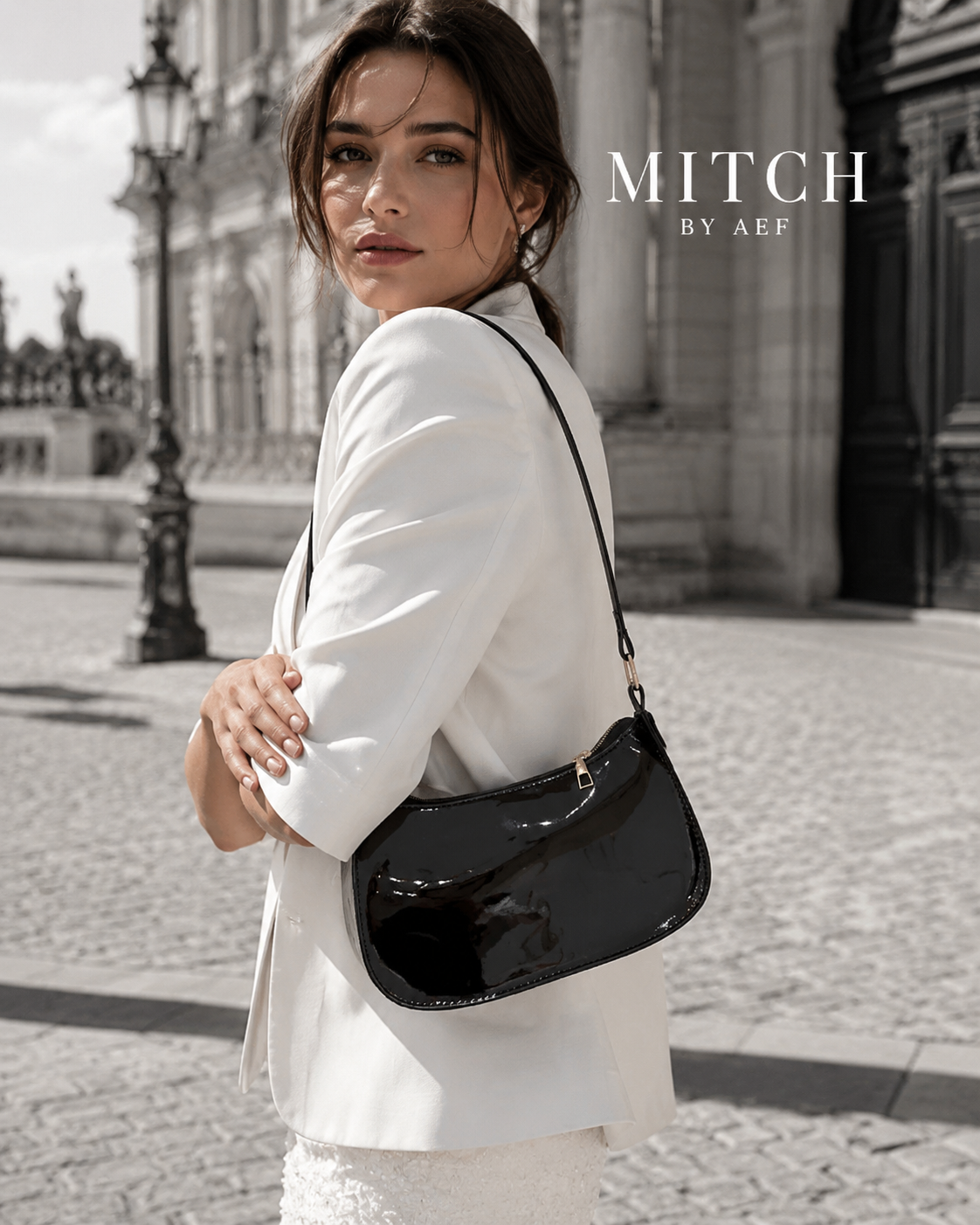 Sac noir verni porté à l’épaule par une femme en tenue blanche élégante à Paris #Mûre Noire