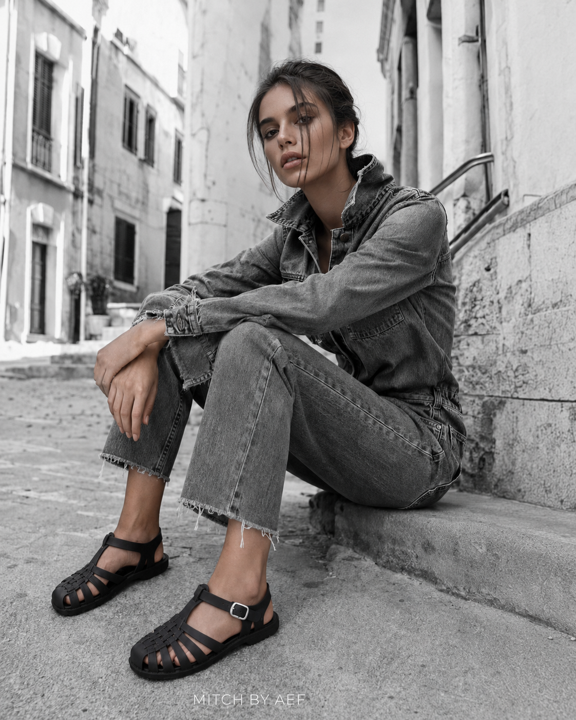 Sandales plates noires pour femme à bout fermé et brides tressées portées avec une tenue en jean
#Noir Profond