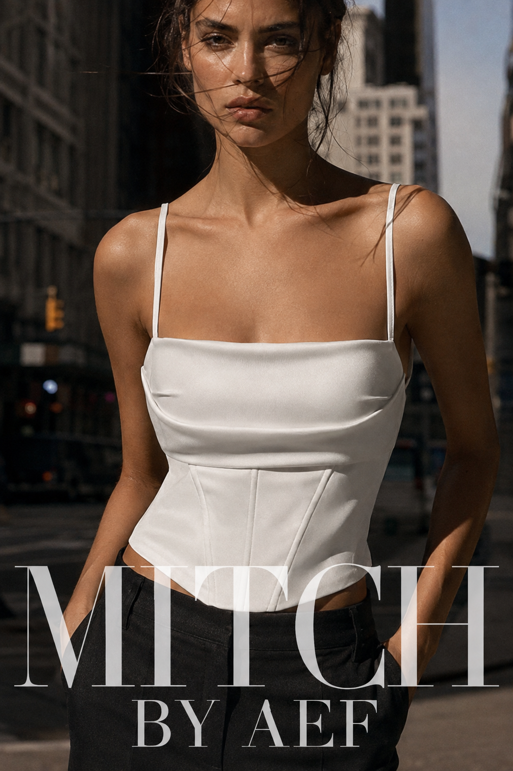 Femme debout dans une rue de New York portant un top corset blanc à fines bretelles et un pantalon noir. #Blanc